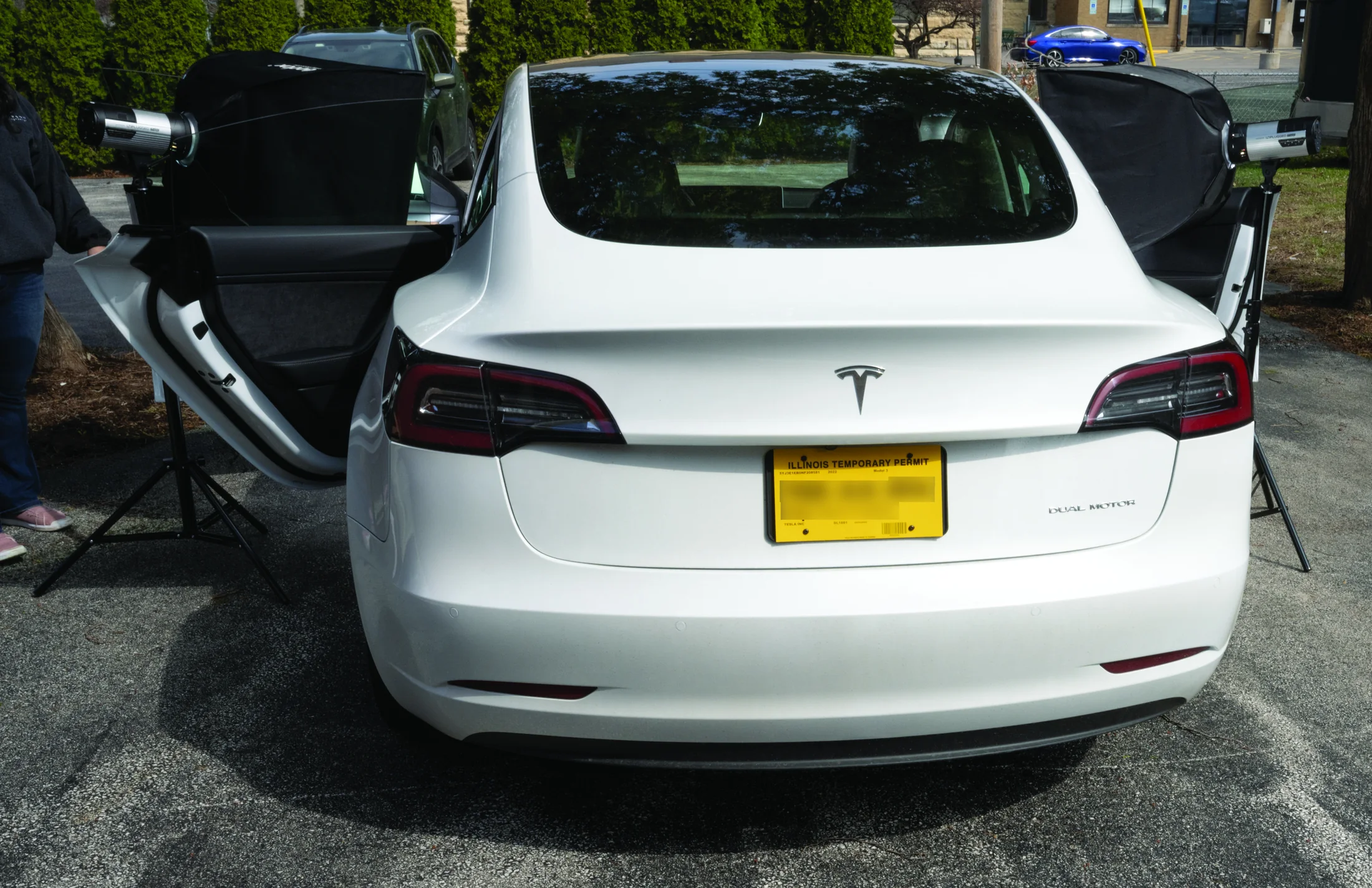 White Tesla outdoors with large lighting modifiers positioned on both sides
